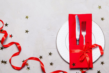 Valentines day table setting with fork, knife, plate and red dinner napkin on grey background, Top view