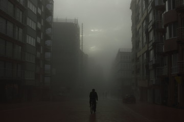 Cyclist on a street in foggy city