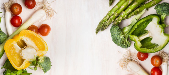 Various vegetables for tasty cooking with asparagus,paprika, tomatoes, broccoli and onions on white wooden background, top view, frame, banner. Healthy vegetarian food or diet nutrition concept