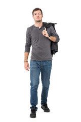 Wall Mural - Casual young man walking forward carrying jacket over shoulder looking at camera. Full body length portrait isolated over white background.