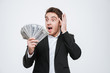 © Drobot Dean - Surprised businessman standing at studio holding money