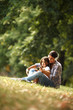 © BalanceFormCreative - Mother and daughter sitting on grass and listening to music on smart phone.