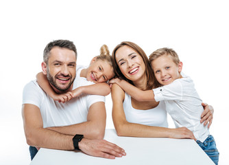 Smiling family in white t-shirts hugging