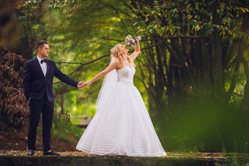 Wall Mural - Bride and groom in a park kissing.couple newlyweds bride and groom at a wedding in nature green forest are kissing photo portrait.Wedding Couple