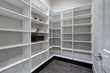 Empty pantry interior with white shelves and dark floor