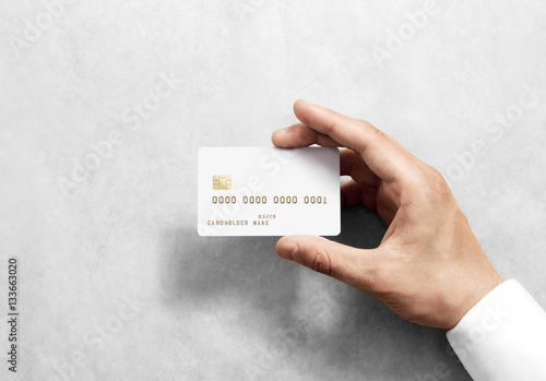 Fotografering Hand holding blank white credit card mockup with chip and embossed gold info