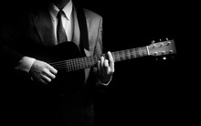 Male Musician In Suit Playing Acoustic Guitar, Black And White. Isolated On Black