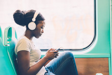 Young Black Woman Listening Music Travelling By Bus Using Smart Phone Hand Hold, Pensive - Thoughtful, Thinking Future, Music Concept