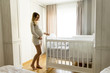 © BGStock72 - Pregnant woman setting up baby crib smiling