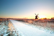 © Olha Rohulya - snow on bike path and sun behind windmill