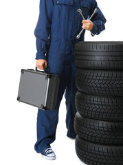 Young mechanic in uniform with spanner and wheels, on white background