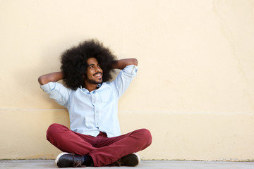 smiling man sitting on floor leaning on wall