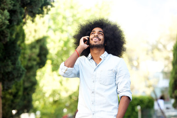 happy man standing outside in nature with mobile phone