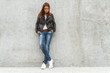 © perfectlab - Portrait of a beautiful girl in jeans and a black leather jacket from the concrete wall