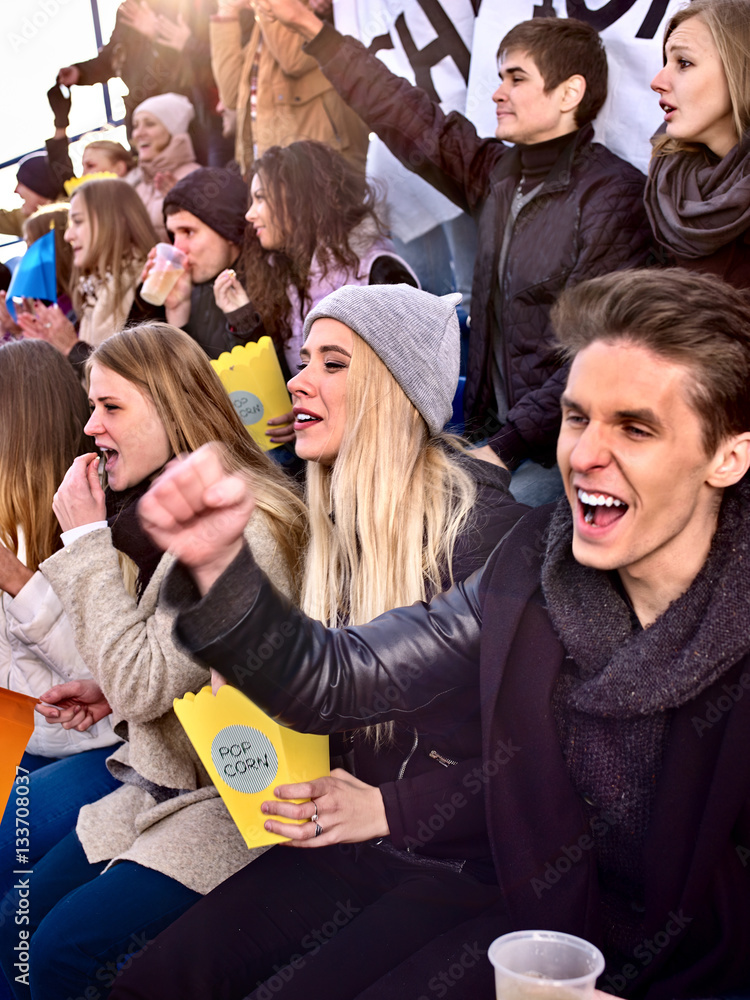 Fans cheering in stadium and eating popcorn. Group young people friends ...