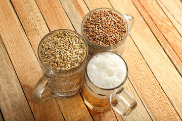 Canvas Print - Glasses with fresh beer, wheat and barley on wooden background