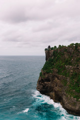 The pictersque rock in the ocean with the temple on te top. Azure waves with white foam of Indian ocean, Indonesia, Bali, Uluwatu