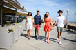 © W PRODUCTION - Group of young people man and woman walking on seaside of touristic resort during a sunny summer day