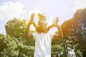 African American father and son piggyback in outdoor park