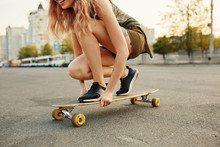 Beautiful young girl with tattoos sits on longboard in sunny weather