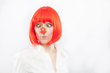 Pretty Young Brunette Caucasian Woman With Red Nose And Wig Making A Face On White Background