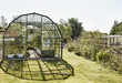 © Mint Images - A person tending plants in a greenhouse in a garden.