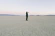 © Mint Images - Man taking photo with smart phone, standing in vast desert playa, Black Rock Desert, Nevada
