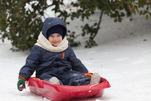 Happy Little Boy On His Sled In Winter Snow