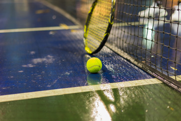 Tennis ball, racquet and net on wet ground after raining