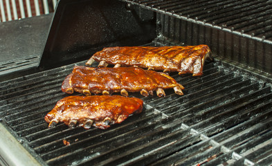 Three racks of pork ribs grilling on the barbecue
