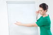 © yurkos - Full length portrait of a happy beautiful businesswoman standing with blank flipchart isolated on a white background. Looking at camera