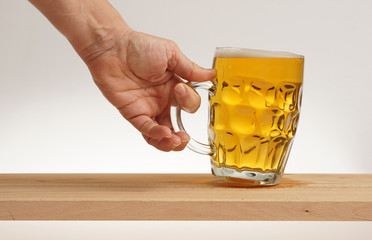 Hand take glass of light beer from wooden board.