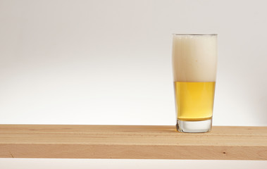 Glass of light beer on a wooden board.