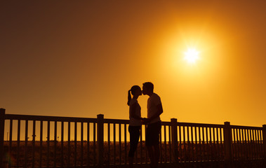 Wall Mural - Couple kissing at sunset. 