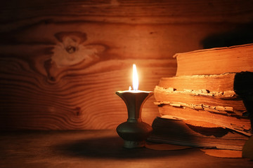 Wall Mural - old tattered book on a wooden table lighted candle and glasses