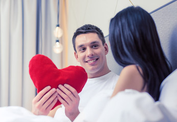 Wall Mural - smiling couple in bed with red heart shape pillow