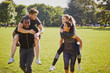 © Connect Images - Men and women having fun training in park, having piggy back  race