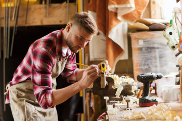 Wall Mural - carpenter with ruler measuring plank at workshop