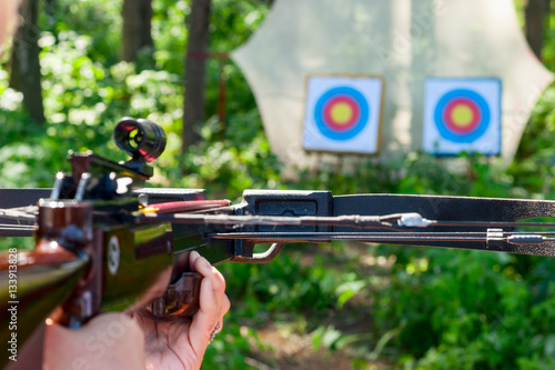 Woman aiming crossbow at target Tableau sur Toile