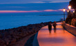 People walk on the seafront in little town of Grado at sunset. Italy.