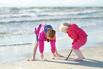 Two little sisters having fun on a sandy beach of Baltic sea