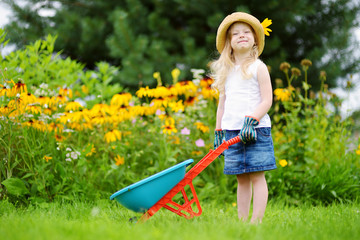 Adorable little girl having fun with a toy wheelbarrow