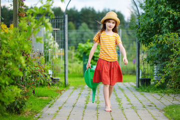 Wall Mural - Cute little girl watering flowers in the garden