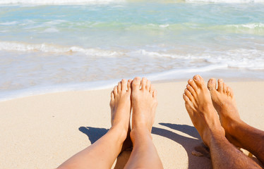 Romantic beach holiday. Couples feet on the beach. 