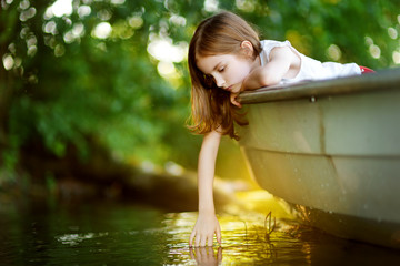  Cute little girl having fun in a boat by a river