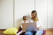 © Cavan Images - Happy mother and daughter using laptop at home