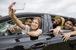 © Cavan Images - Happy friends taking selfie while sitting in the car