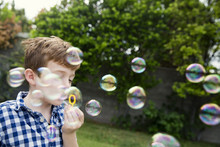 Boy Blowing Bubbles In Yard