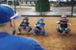 © Cavan Images - Rear view of coach training baseball catchers on field