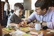 © Cavan Images - Father and son coloring menu together in the restaurant